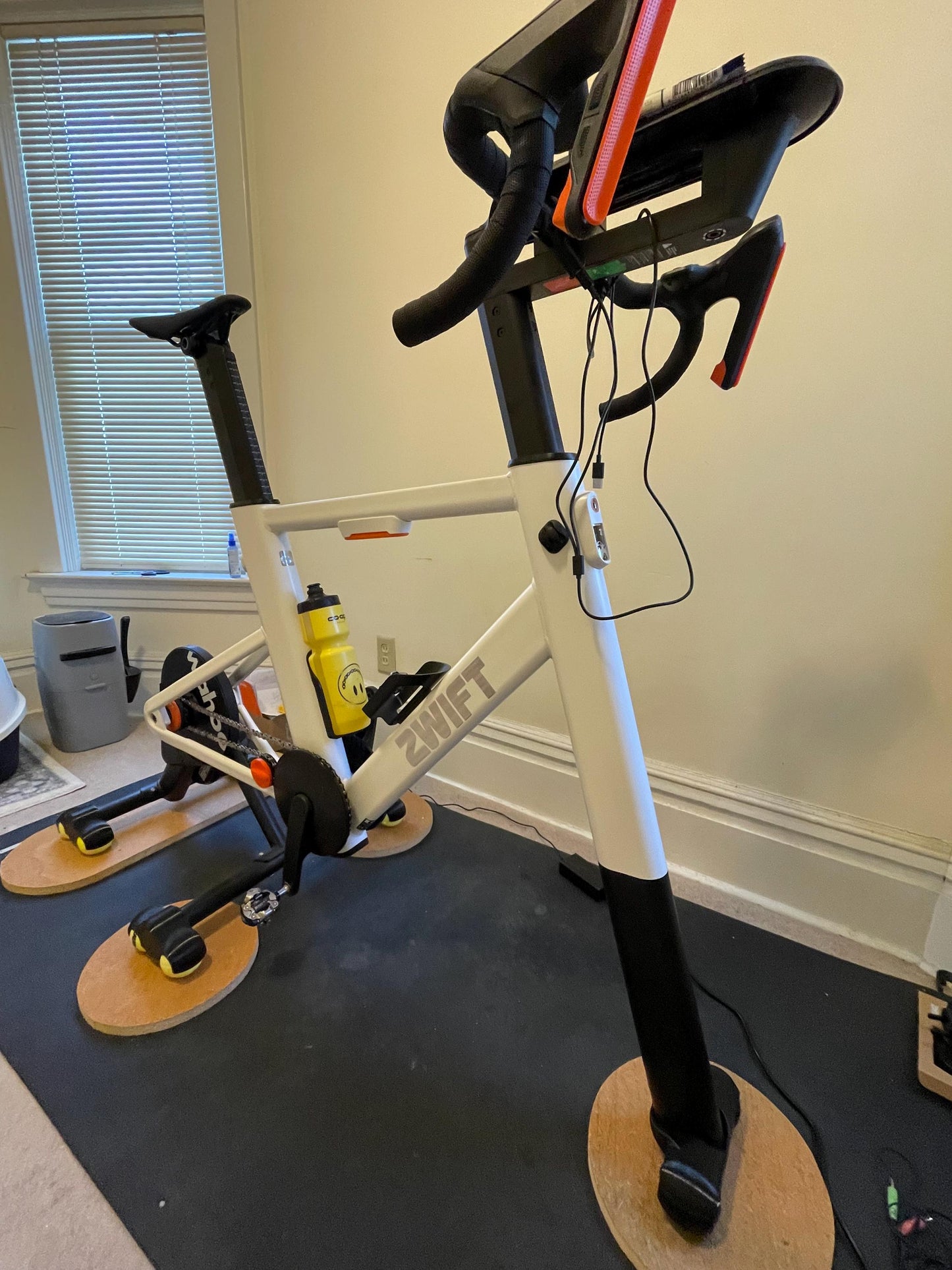 Bicycle trainer setup indoors with a window in the background