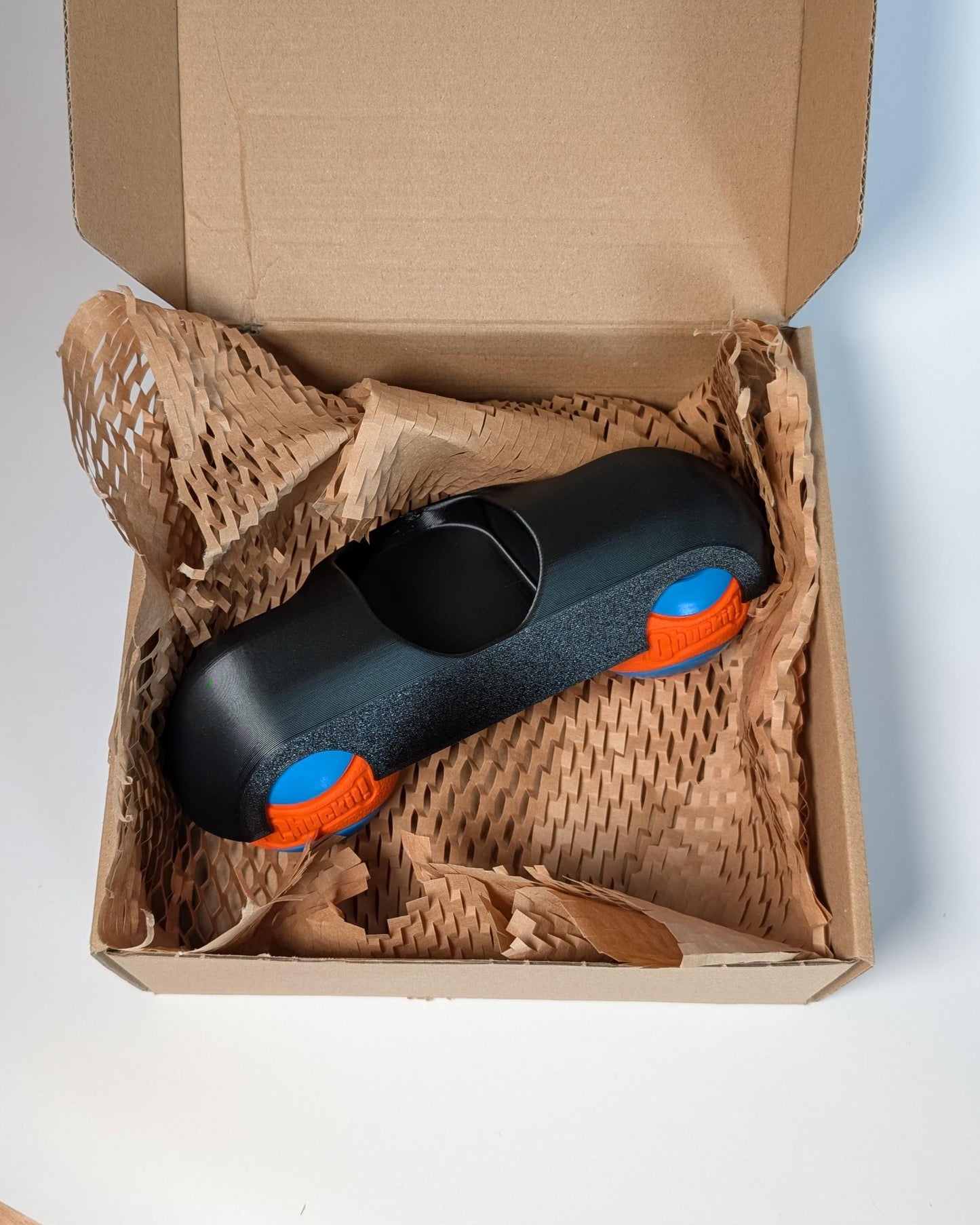 Zwift ride frame rocker foot in a cardboard box with brown packing material.