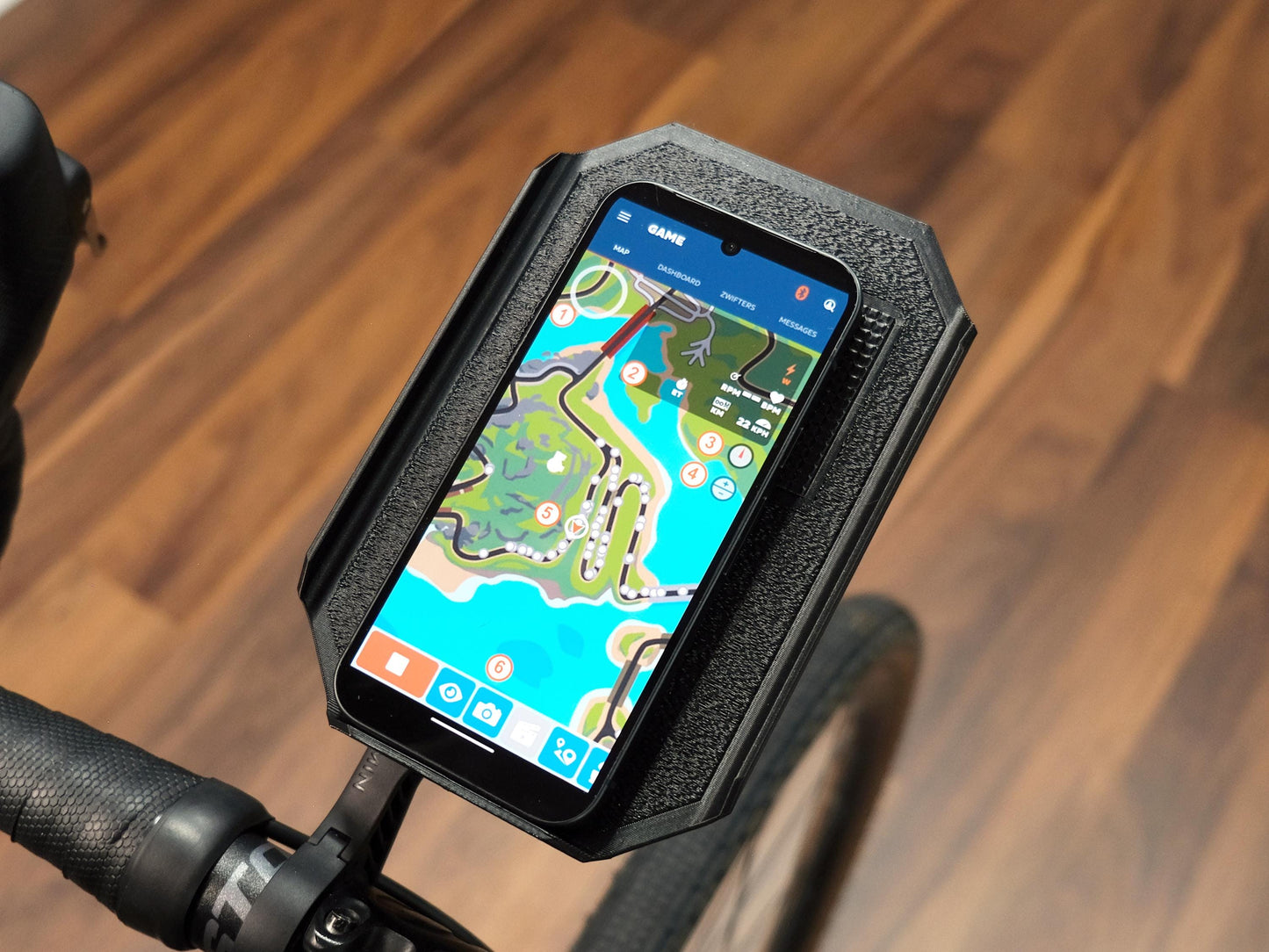 Phone mounted on a bike handlebar with zwift companion app displayed on the screen.