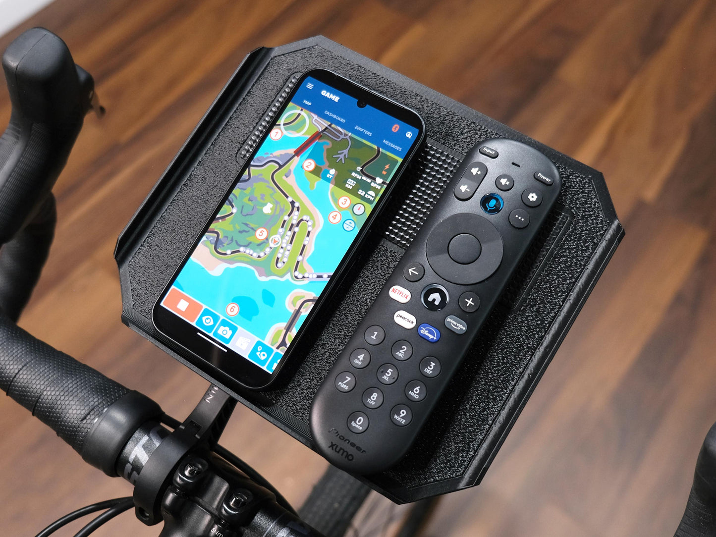 Trainer tray holding a tv remote and a phone displaying the zwift companion app