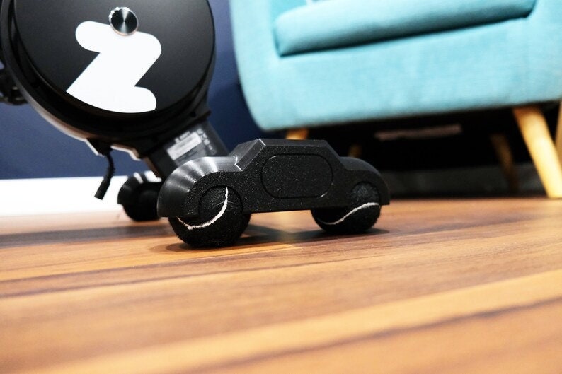 low angle view of a black tennis ball with zwift hub one rocker feet with wood flooring