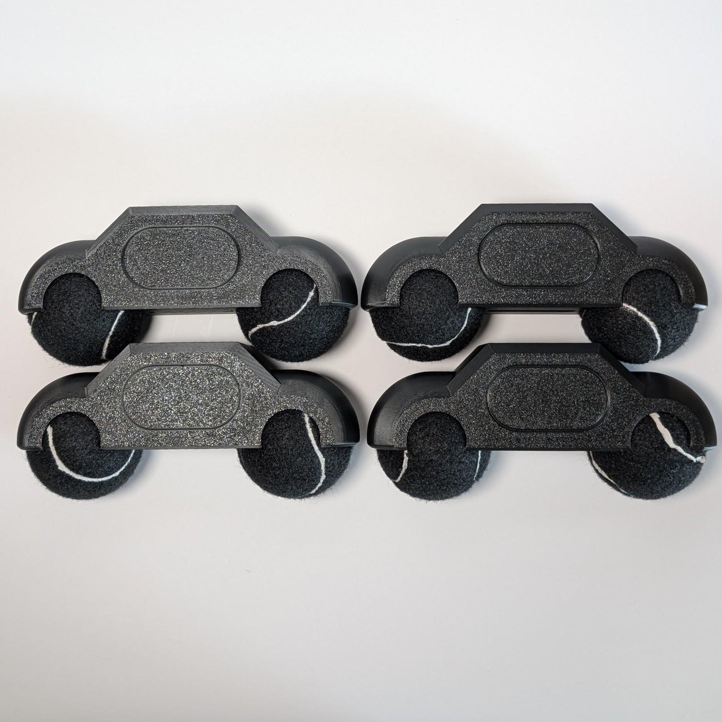 set of four zwift hub one tennis ball holders with black tennis balls on a white background
