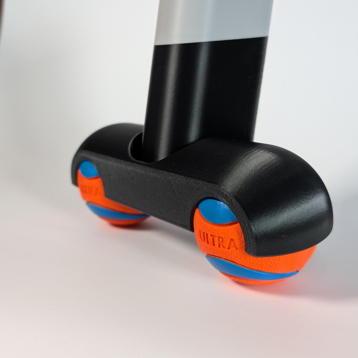 Close up of a zwift ride frame rocker foot with chuck-it balls on a white background