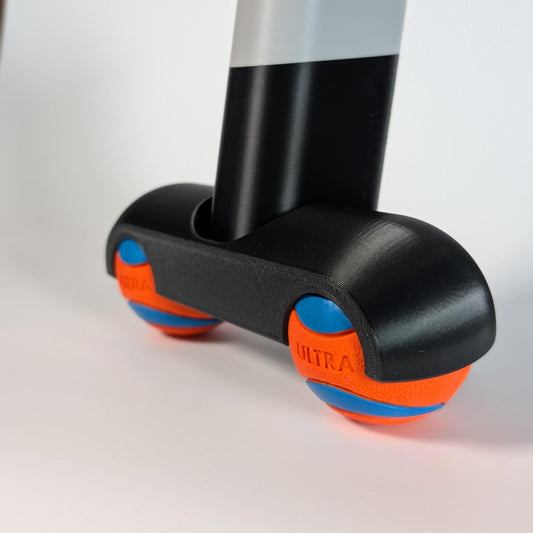 Close up of a zwift ride frame rocker foot with chuck-it balls on a white background