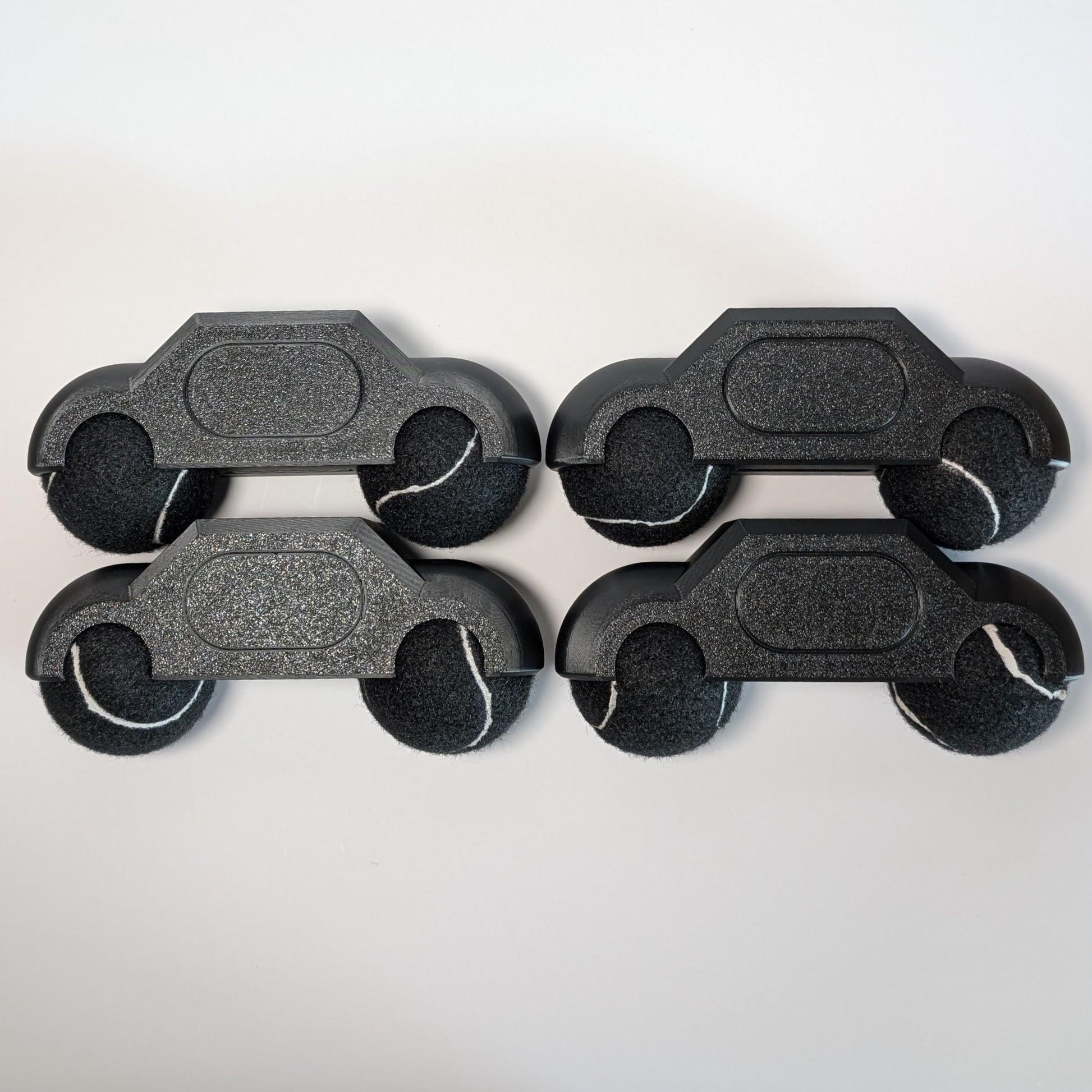 set of four zwift hub one tennis ball holders with black tennis balls on a white background